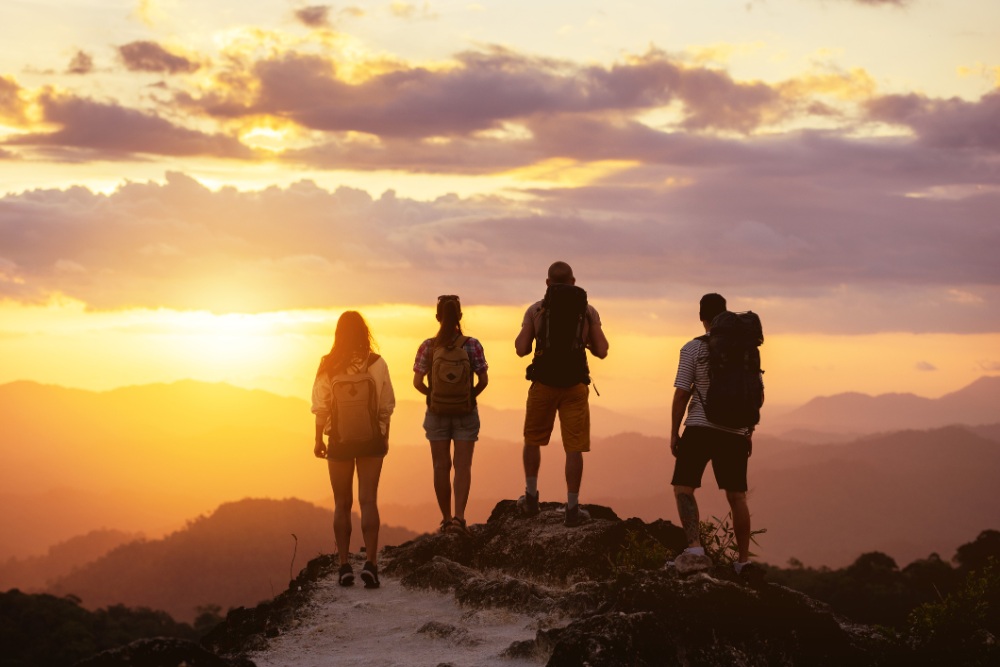 people silhouettes on mountain top at sunset